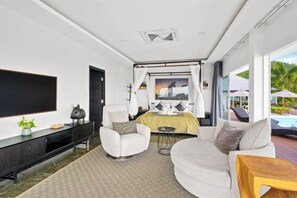Une chambre d’hôtel moderne dotée d’un grand téléviseur à écran plat, d’un canapé confortable, d’un petit fauteuil et d’un lit à baldaquin.