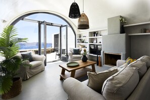 Una sala de estar moderna con un amplio ventanal arqueado, chimenea y una zona de estar acogedora.