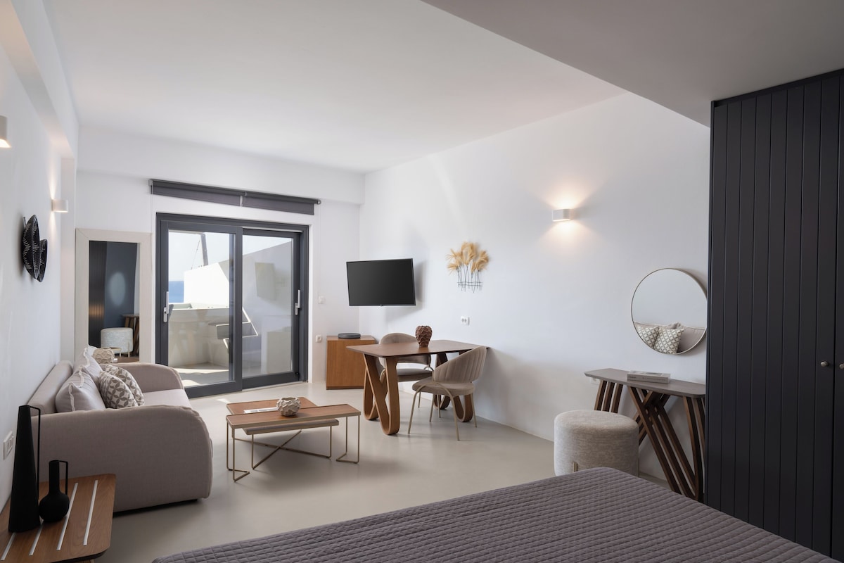 A modern living room with a sofa, coffee table, TV, and dining area.