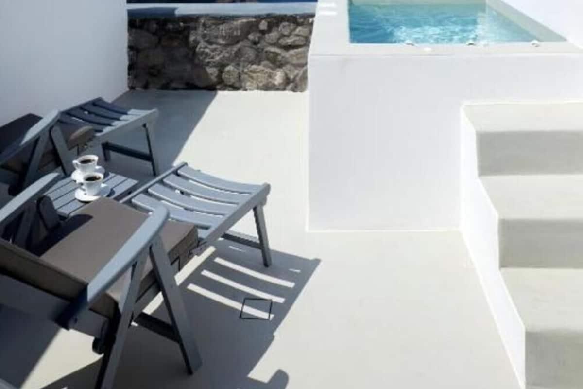 A rooftop terrace with a pool, lounge chairs, and a view of the sea.