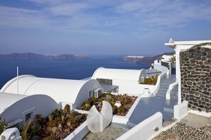 Un edificio blanco con pared de piedra y vista al mar.