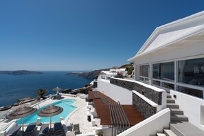 A modern hotel with a pool, outdoor seating, and a view of the sea. - Santorini Princess Spa Hotel (Santorini)