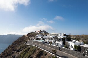 A coastal village with white buildings, a winding road, and a view of the sea.