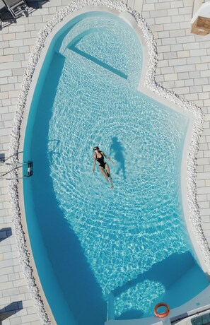 A swimming pool with a curved edge, a lifeguard chair, and a pool ladder. - Santorini Princess Spa Hotel (Santorini)