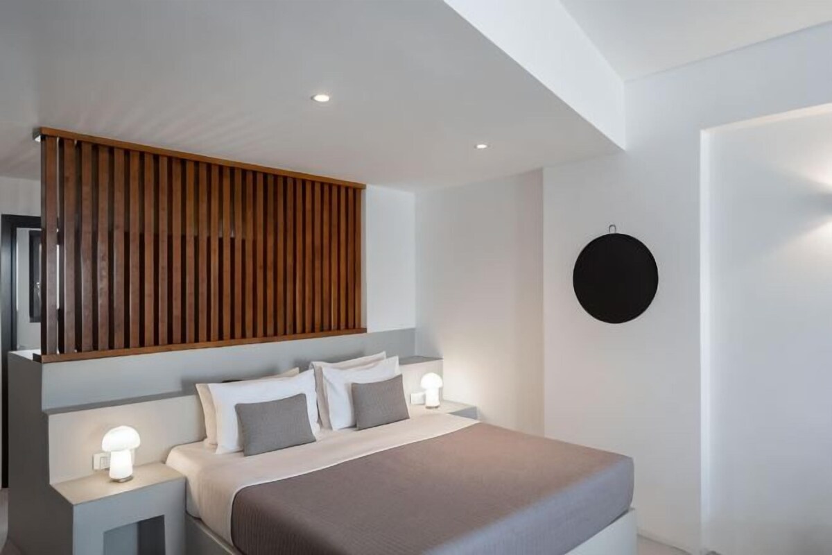 Une chambre à coucher moderne avec un lit, des tables de chevet, un panneau en bois et un élément décoratif rond fixé au mur.