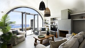 Un salon moderne doté d’une grande fenêtre en arc de cercle, d’une cheminée et d’un coin salon confortable.