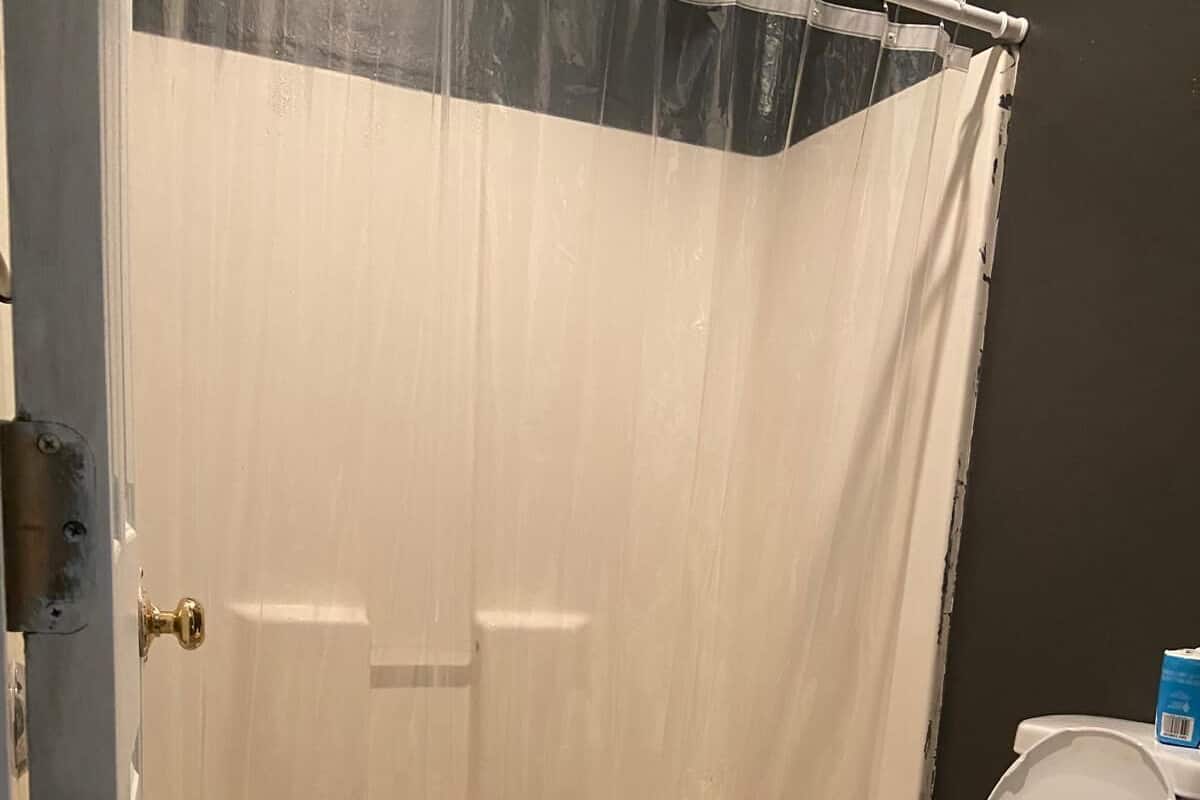 Un baño con cortina de ducha, inodoro y bañera.