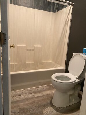 Bañera con ducha, toallas, jabón, shampoo