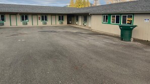 A motel with a central parking area and multiple rooms with green trim. - Glendale Inn (Glendale)