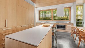 Una cocina moderna con armarios de madera, una isla grande y vistas a bambú.