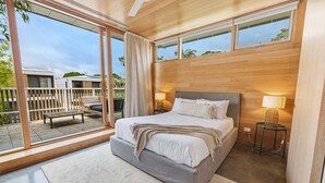 Un dormitorio moderno con una cama grande, un balcón y vistas al exterior.