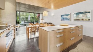 Una cocina moderna con armarios de madera, una isla grande y un comedor con sillas de mimbre.