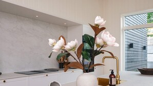 Et moderne køkken med en marmor bordplade, en vase med blomster og en guldbakke med glas.