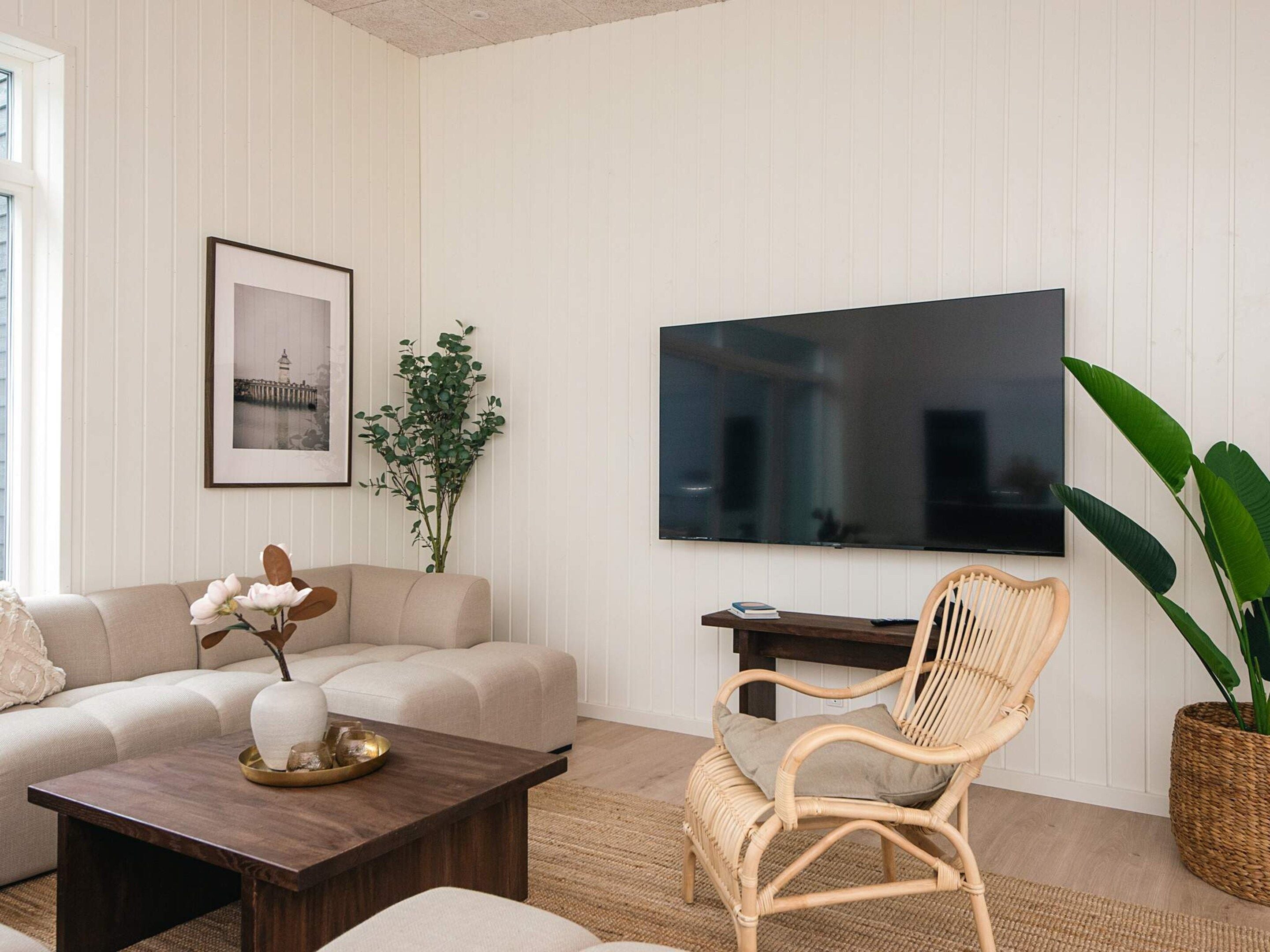 A living room with a sofa, a coffee table, a wicker chair, a television, and a framed picture on the wall.