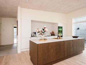 Cozinha moderna com ilha central, armários brancos e vista para o exterior.