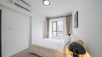 A minimalist bedroom with a bed, a bedside lamp, and a window with curtains.