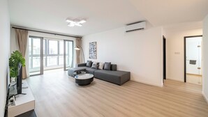 A modern living room with a sectional sofa, a coffee table, and a large window with curtains. - Tyms Spacious 3BR 2BA APT  Laishi Di (Shanghai)