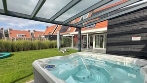 Un bain à remous situé dans un espace extérieur abrité, avec vue sur un quartier résidentiel.