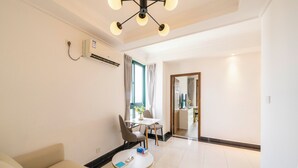 A modern hotel room with a sofa, a round table, and a dining area with chairs. - Tyms Yadu Business 1BR APT   (Shanghai)
