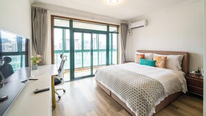 A hotel room with a large bed, a desk with a computer, and a view of the city through a large window. - Tyms Yadu Business 1BR APT   (Shanghai)