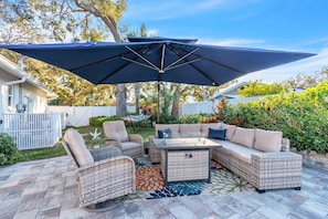 Une terrasse extérieure aménagée avec des meubles en osier, une table et un grand parasol.