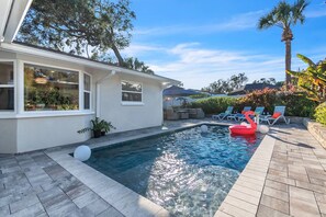 A swimming pool with lounge chairs and a flamingo float.