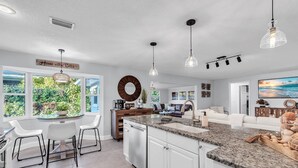 A modern kitchen with a central island, white cabinetry, and pendant lighting. - Updated! Heated Pool! Near Beach! Grill, Parking, Outdoor Oasis! ~ Rosemary's Hacienda (Largo)