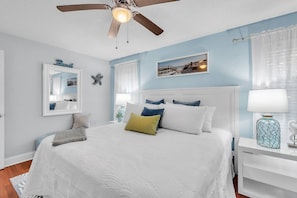 Une chambre à coucher avec un lit, un ventilateur de plafond, une table de chevet et une lampe.