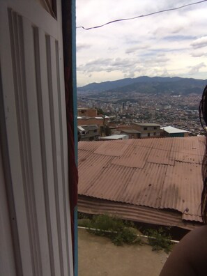 Blick aus einem Fenster auf eine Stadtlandschaft mit Gebäuden und Bergen in der Ferne.