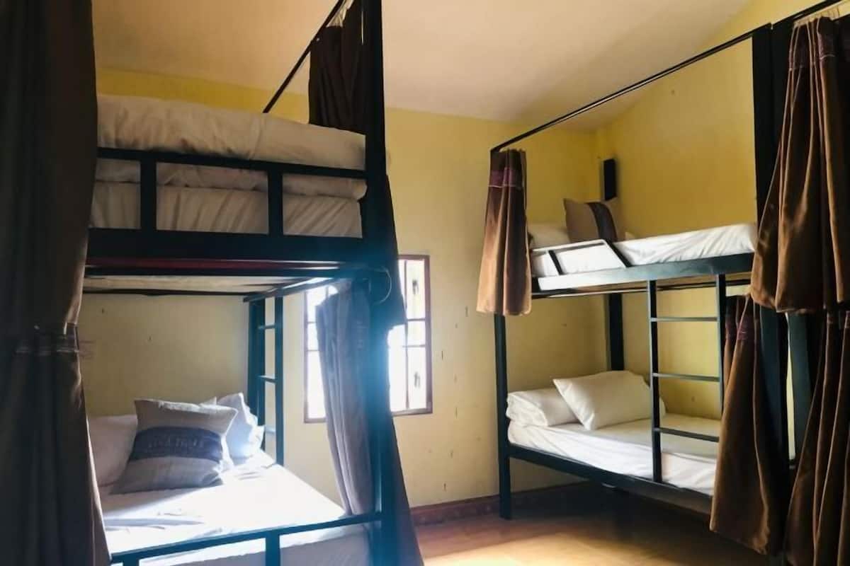 Ein Schlafzimmer mit Etagenbetten, Vorhängen, einem Fenster und einem Bett mit Kissen.