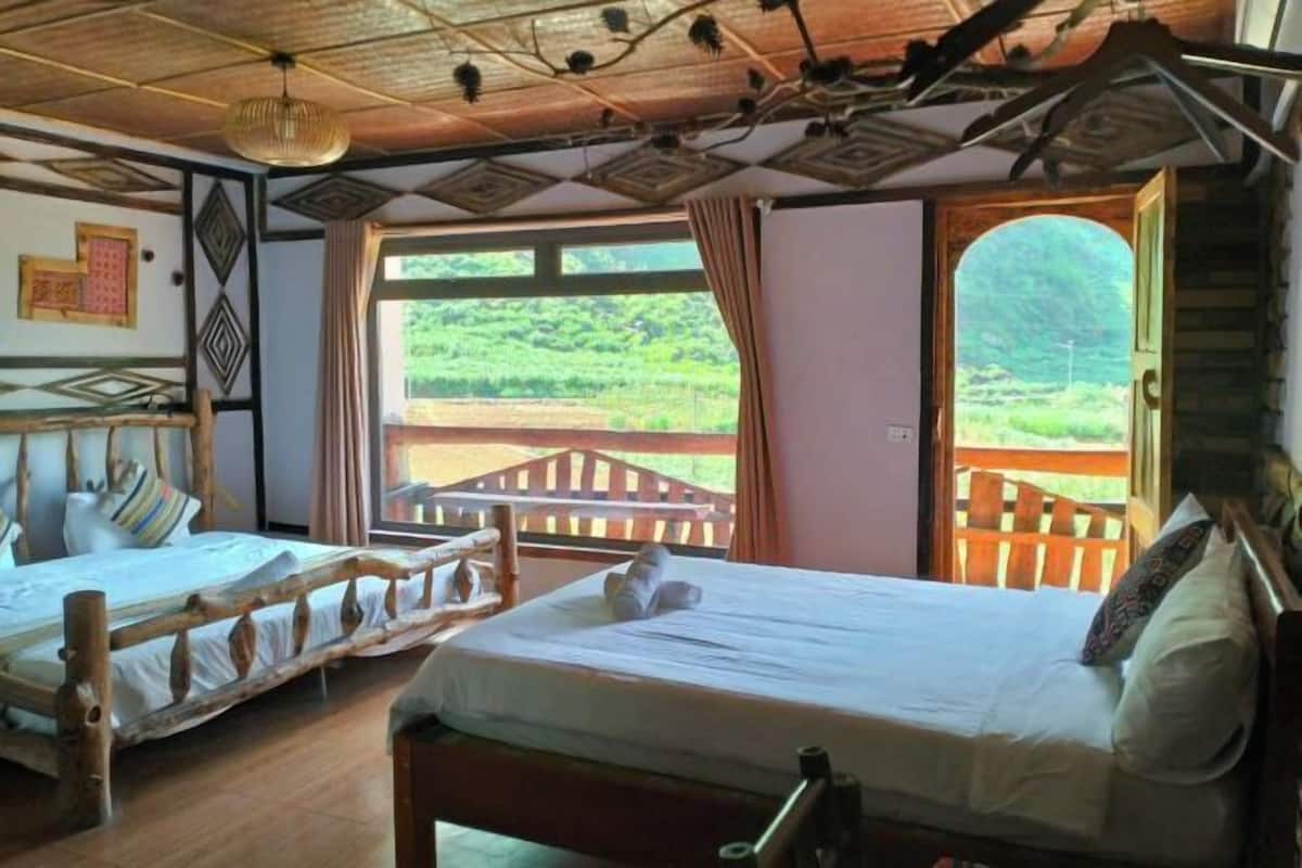 Ein Zimmer mit zwei Betten, Holzbalkendecke und Blick ins Grüne.