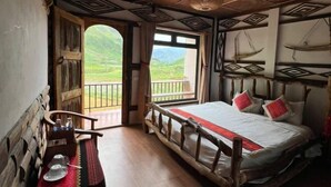 A room with a bed, wooden furniture, a view of green hills, and a balcony. - O'Chau Meo Vac Homestay Ha Giang (Pa Vi)