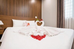 A hotel room with a neatly made bed, a wooden headboard, and a window with curtains. - Be Sea Hotel Da Nang (Da Nang)
