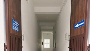 A hallway with wooden doors, a welcome mat, and directional signs. - Kavitha Stay Inn (Namakkal)