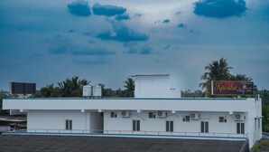 A white building with a flat roof, air conditioning units, and a sign for Kavitha Stay Inn. - Kavitha Stay Inn (Namakkal)