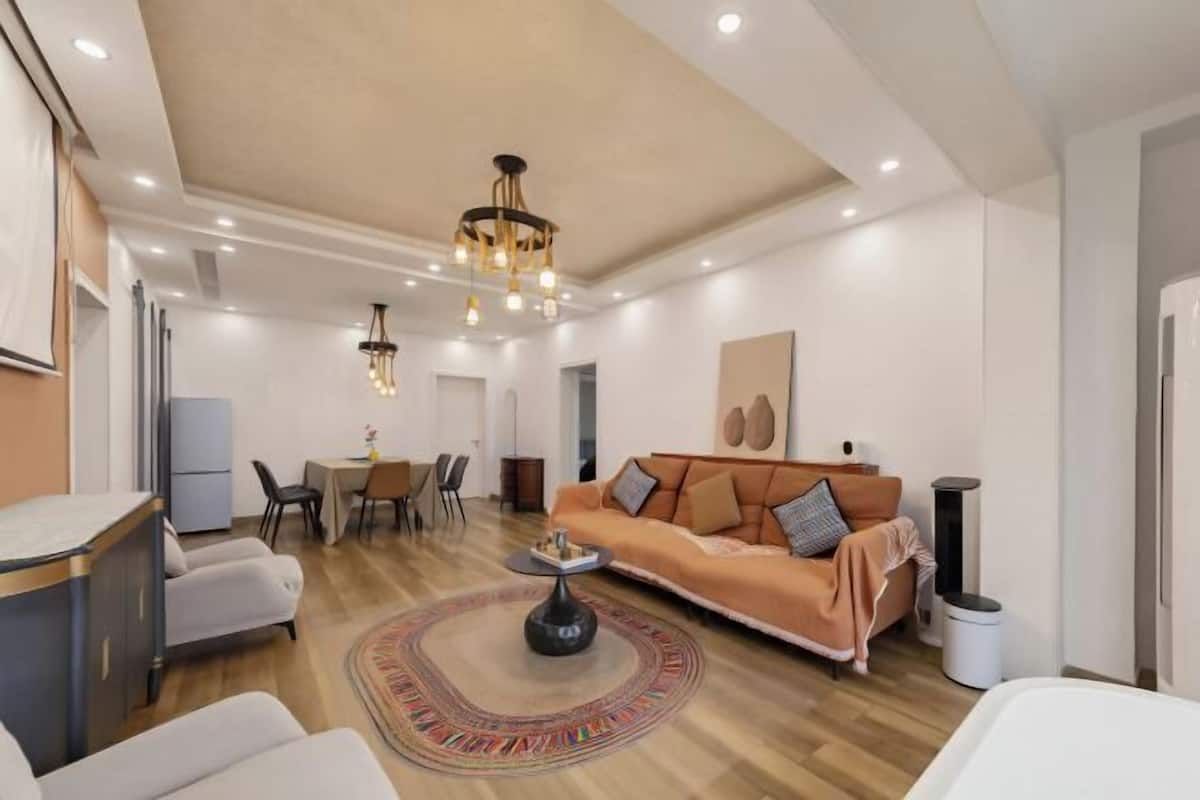 A modern living room with a sofa, coffee table, and a chandelier.
