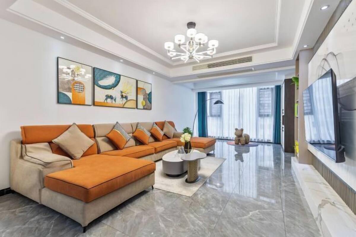 A modern living room with a sectional sofa, a round coffee table, and a flat-screen TV.