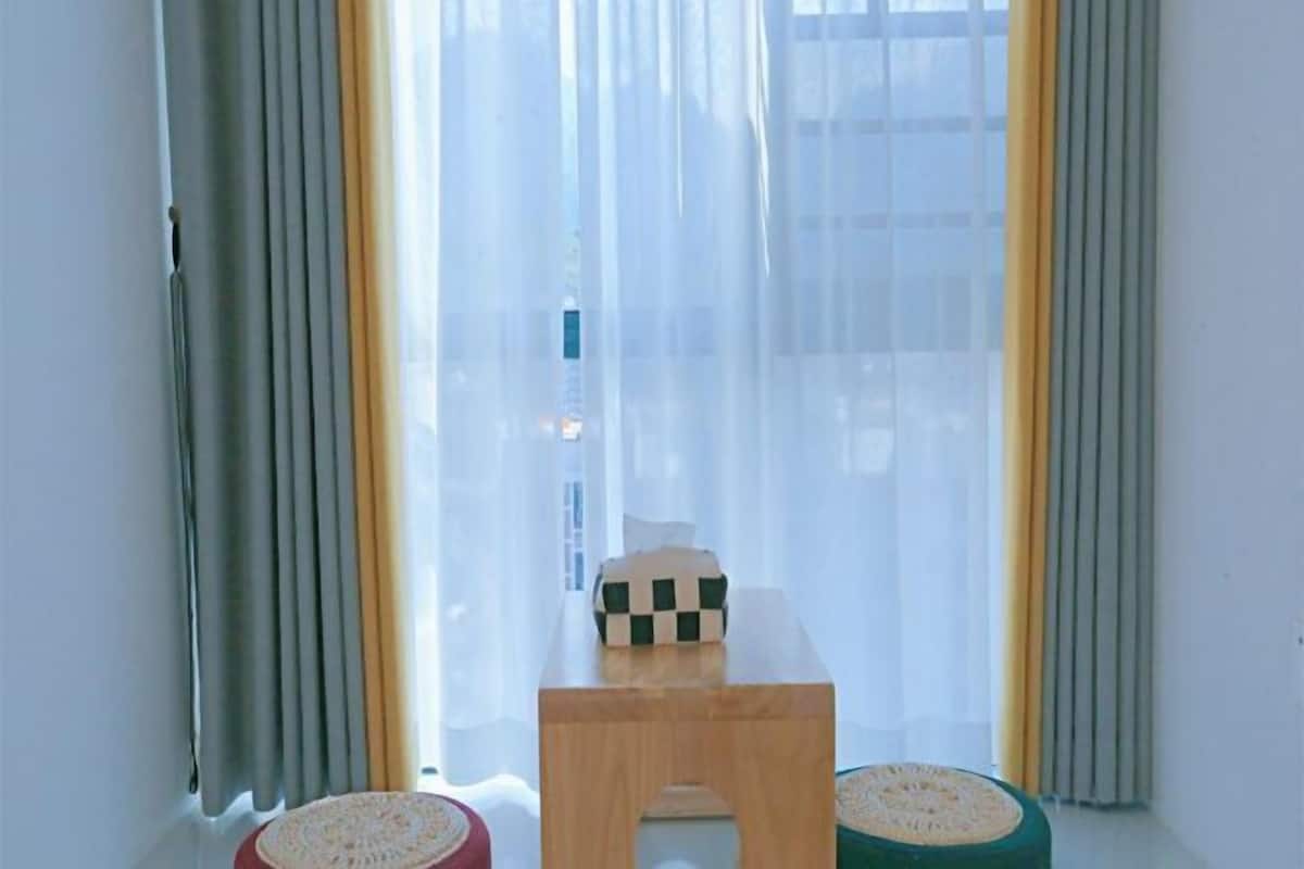A room with a window, a small wooden table, and two stools.