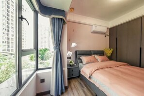 A bedroom with a large window, a bed, a nightstand, a wall-mounted air conditioner, and a view of greenery outside. - My Heart Returns · Zhangjiajie Zero-Pressure Luxury Dream Apartment (Zhangjiajie)
