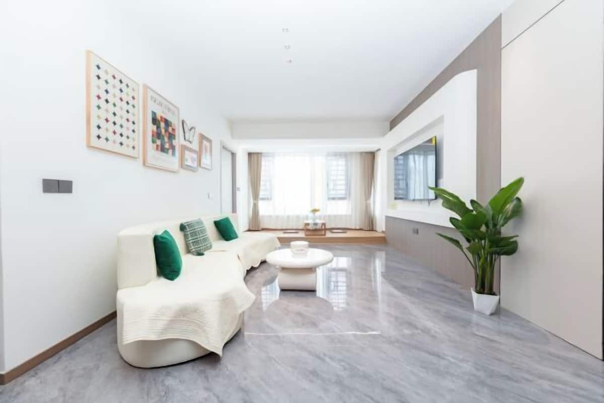 A modern living room with a white sofa, a round coffee table, and a potted plant.