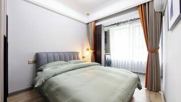 A bedroom with a bed, a nightstand, a lamp, and a window with curtains.