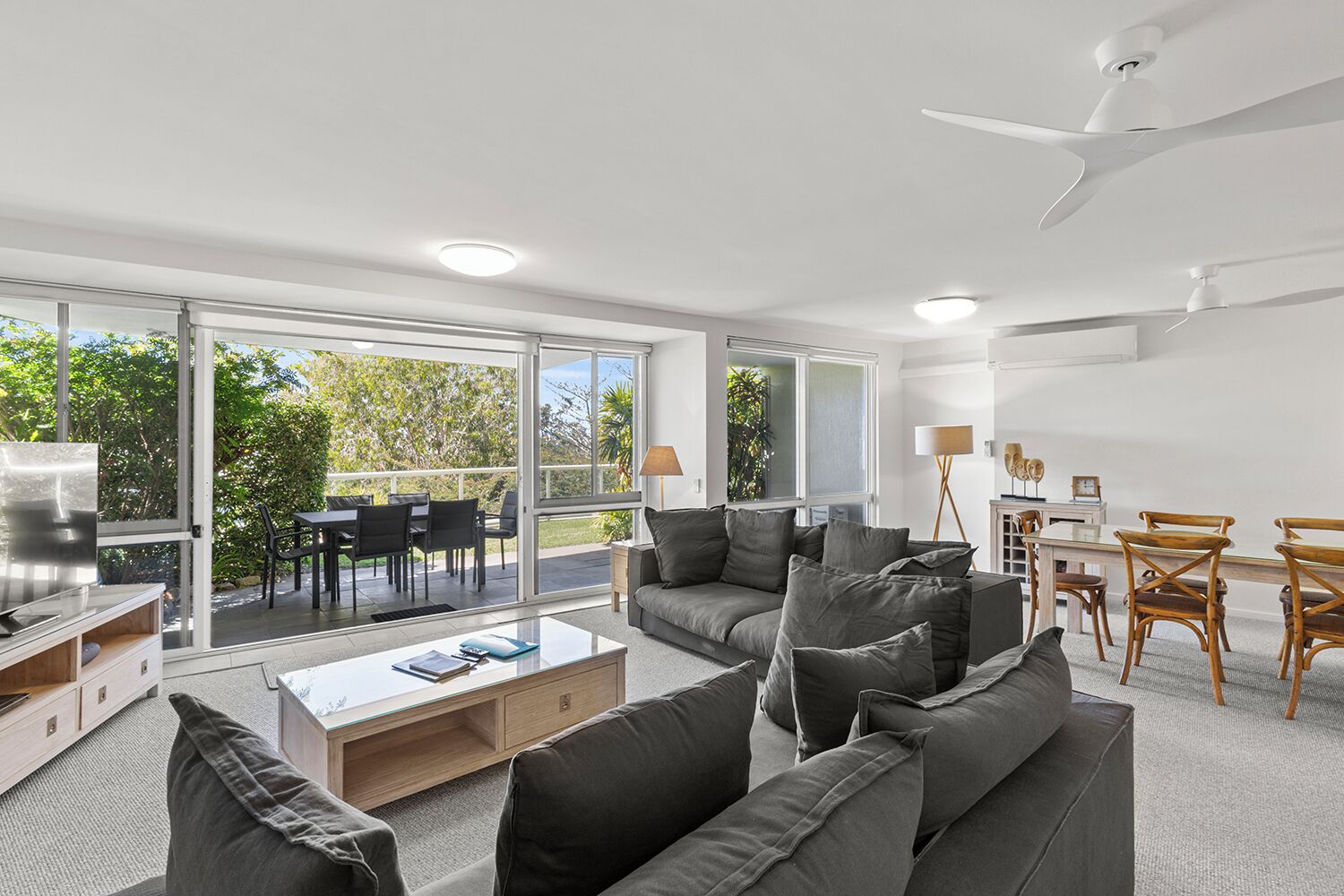 A modern living room with a sofa set, a coffee table, and a dining area with chairs and a table.