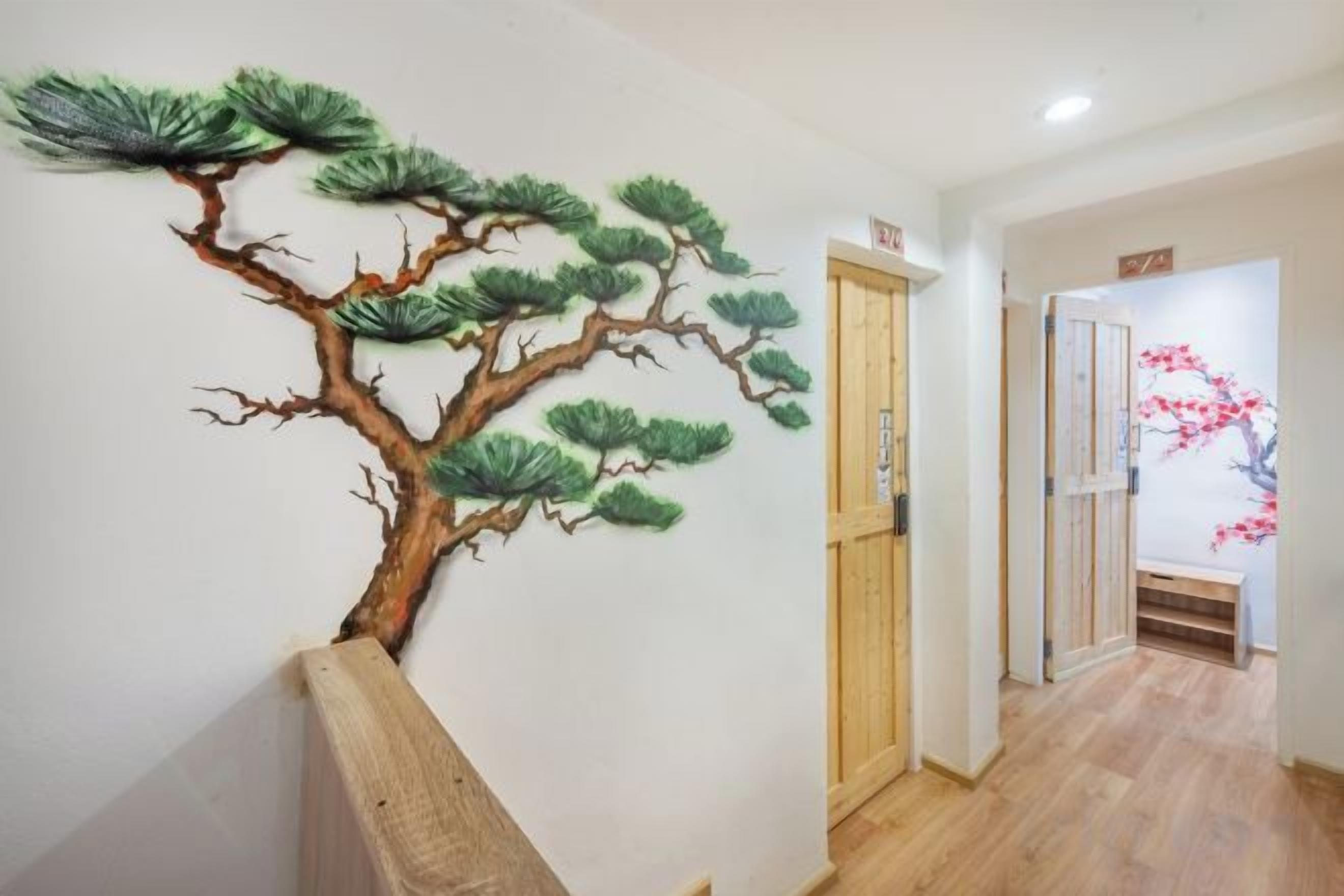 A hallway with a wall-mounted tree mural, a wooden bench, and a door leading to another room.