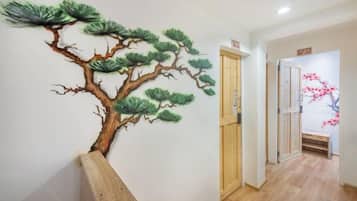 A hallway with a wall-mounted tree mural, a wooden bench, and a door leading to another room.