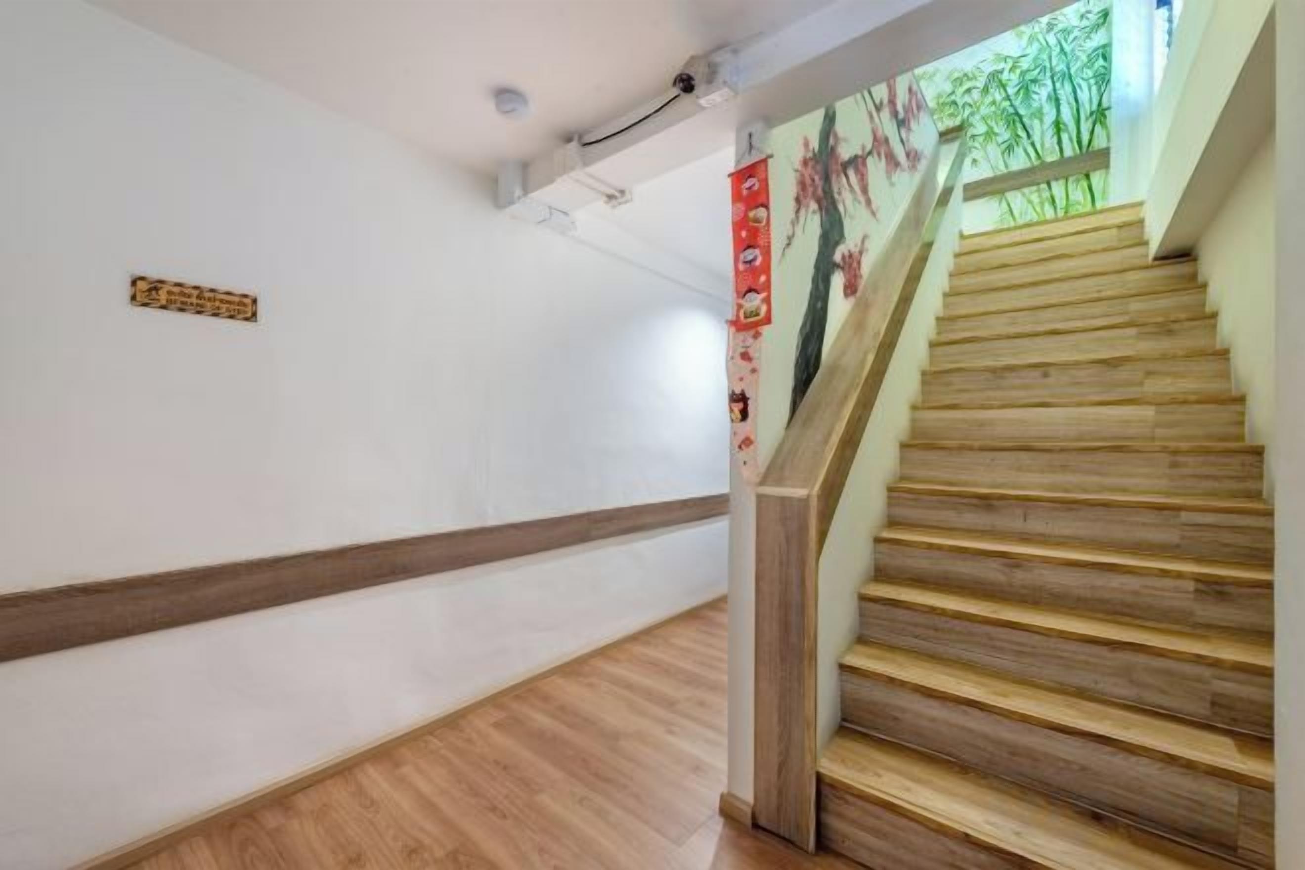 Escadaria com degraus de madeira e corrimão, levando a um patamar com placa fixada na parede.
