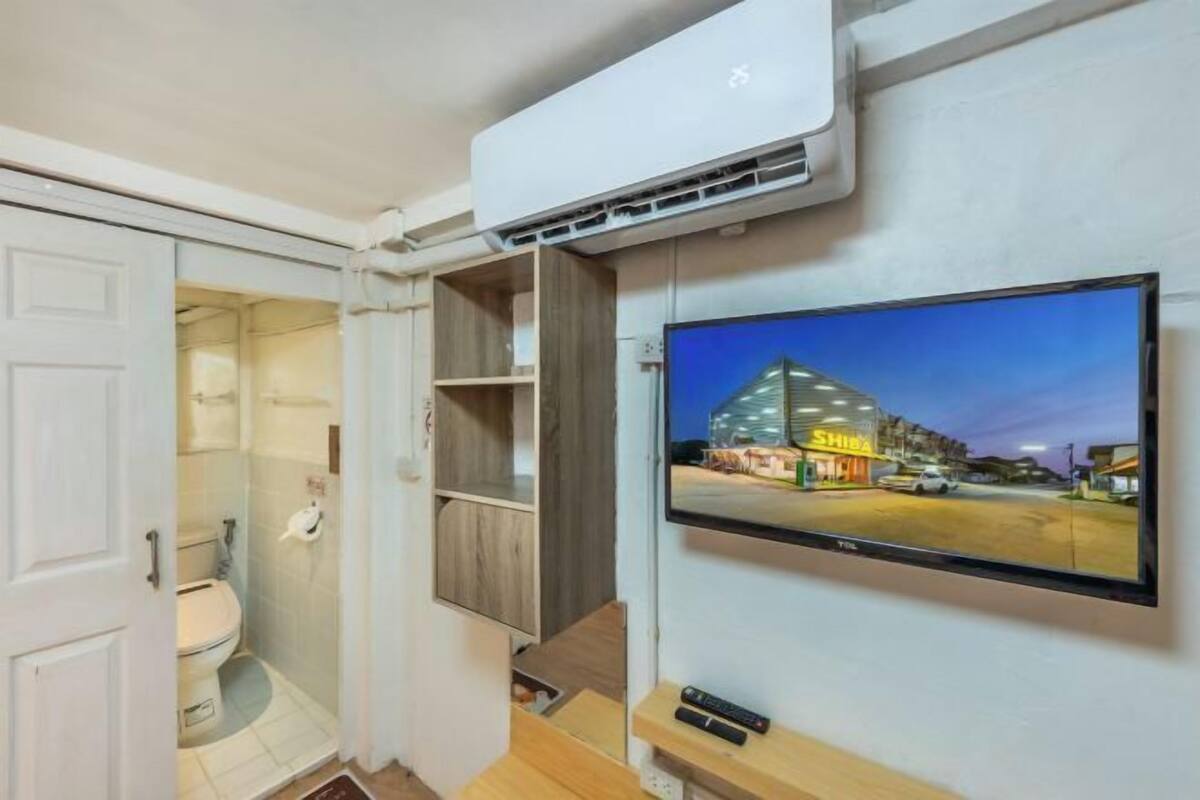 Ein modernes Badezimmer mit Toilette, Dusche und einem an der Wand befestigten Fernseher, der eine Stadtansicht zeigt.