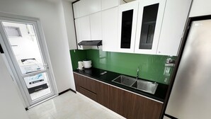 A kitchen with white cabinets, a black countertop, and a stainless steel refrigerator. - Hotel New Life Towel Ha Long (Bai Chay)