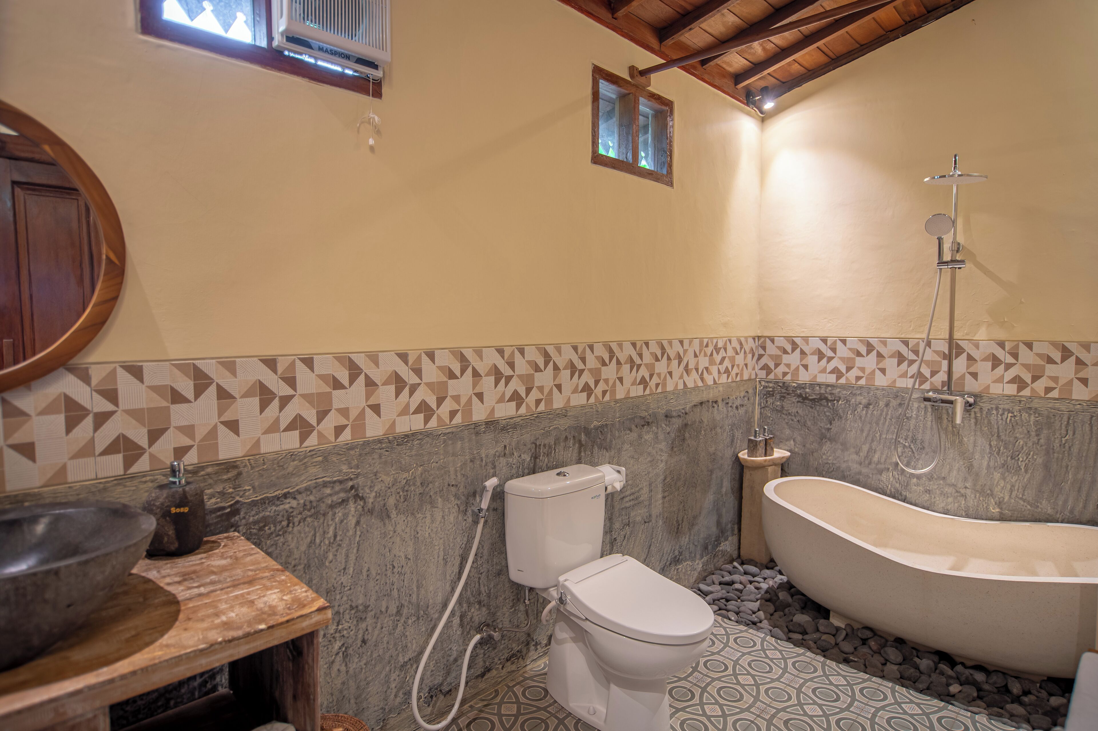 Un baño con bañera independiente, inodoro y lavamanos de piedra.