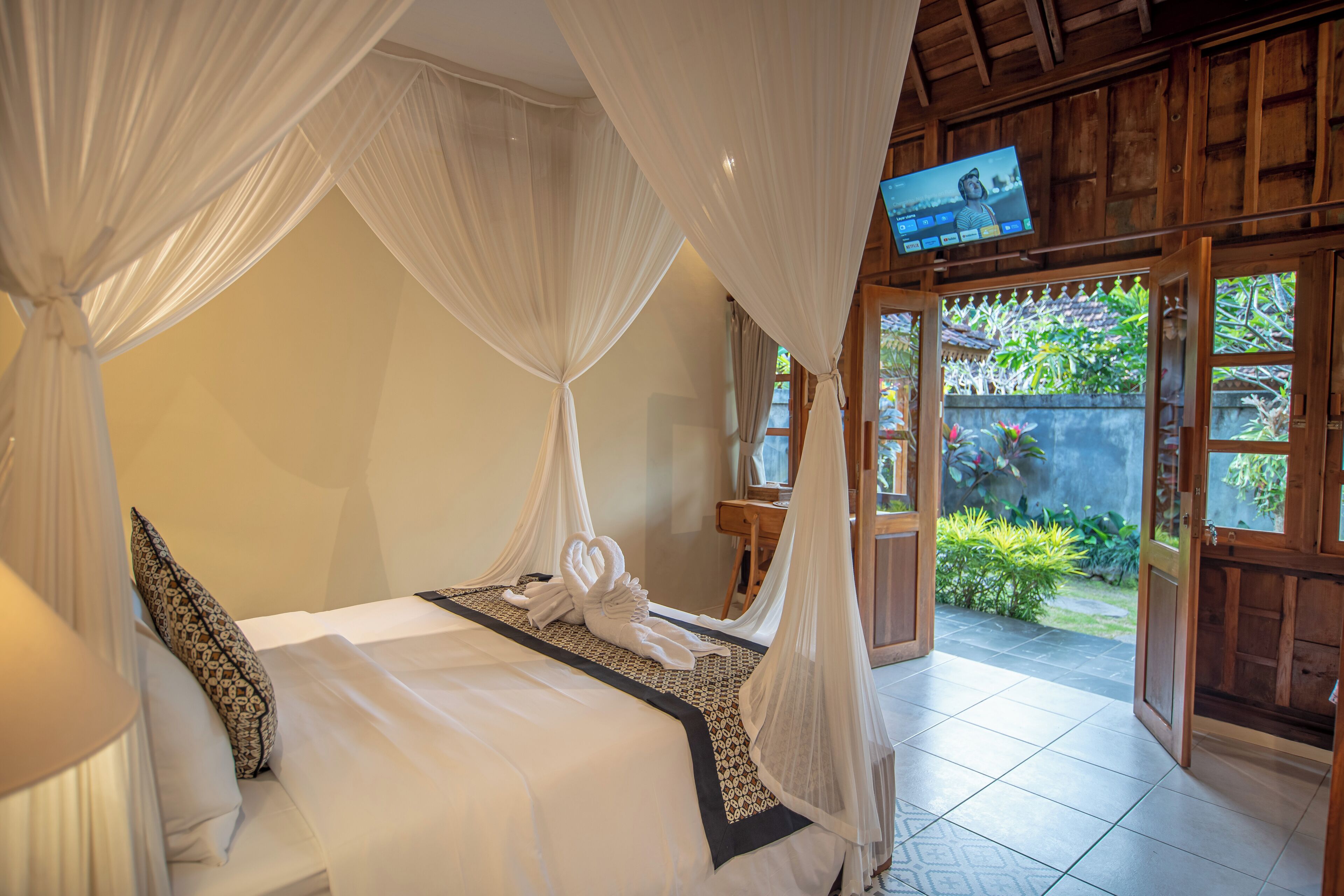 A bedroom with a bed, a TV, and a view of the garden.