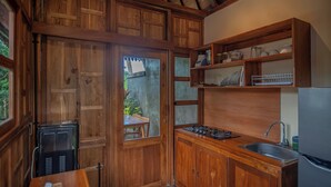 A compact kitchen with wooden cabinetry, a built-in sink, and a small countertop. - Kerjim Wooden Villa (Sukawati)